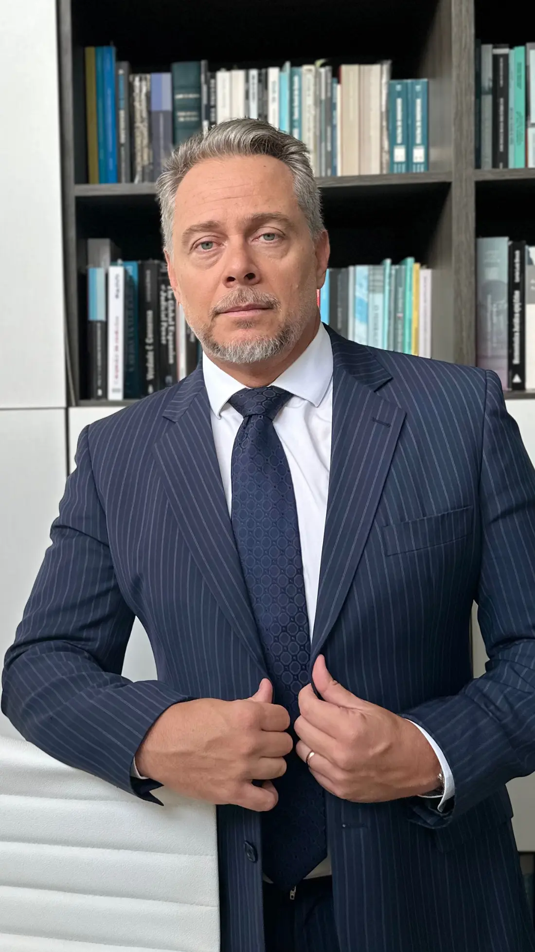 Leandro Corrêa de Oliveira, de terno, em frente a uma estante de livros